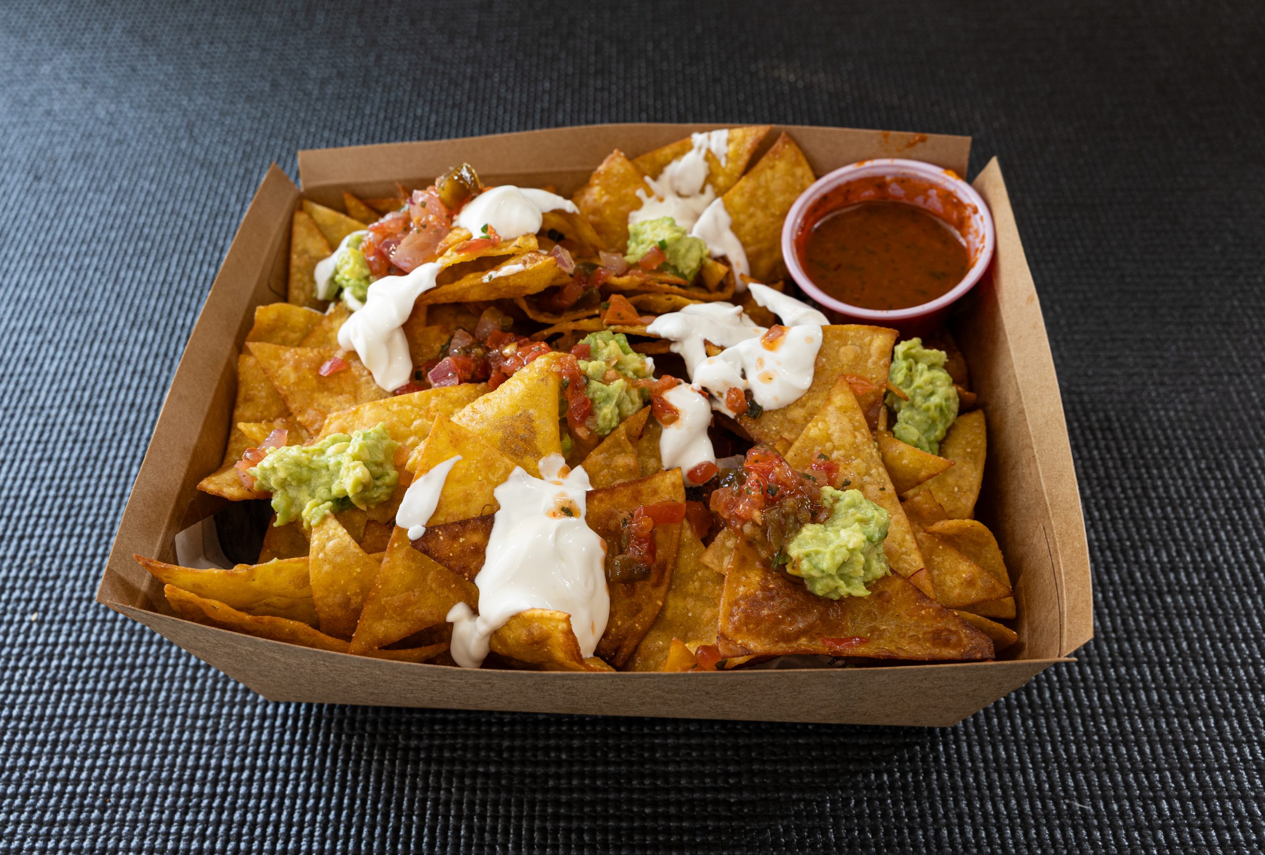 ración de nachos o totopos con tres salsas y pico de gallo casero en envase biodegradable
