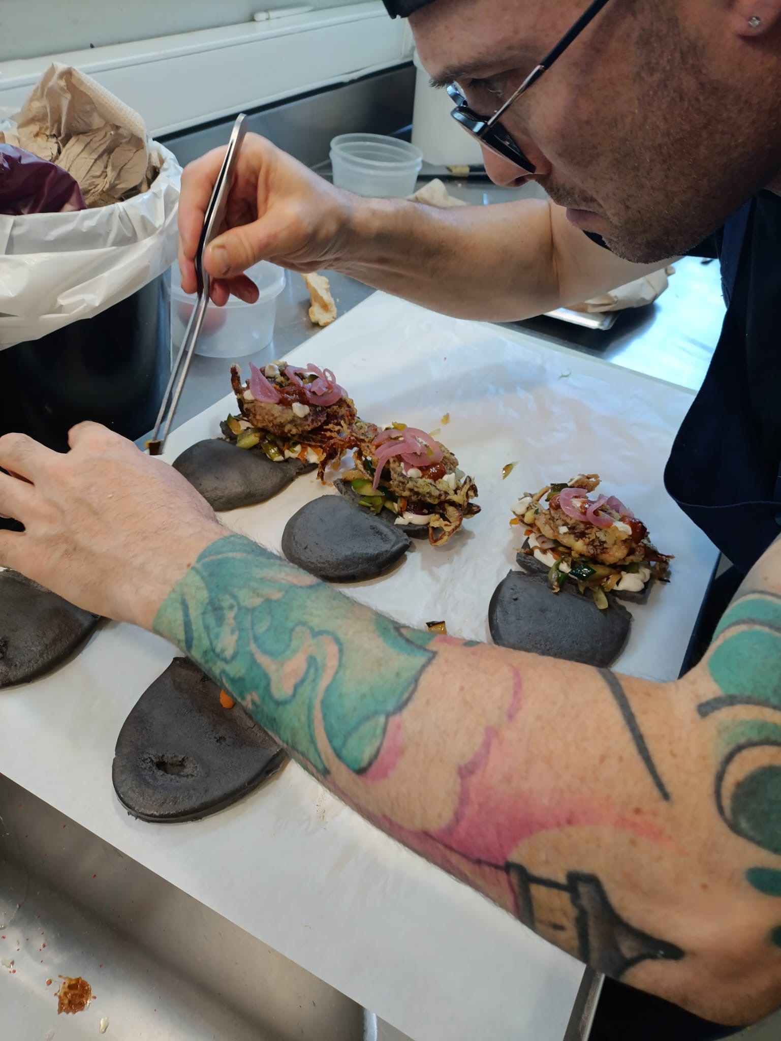 Chef preparando baos artesanales con pan negro en cocina profesional